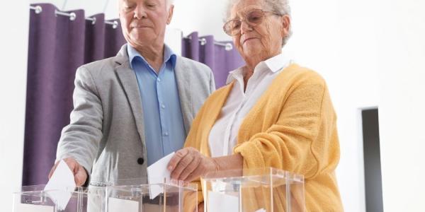 Un hombre y una mujer depositan sus votos en una urna