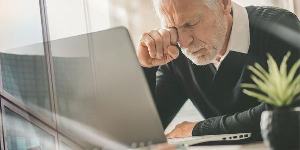 Una persona mayor con gesto de frustración ante un ordenador.