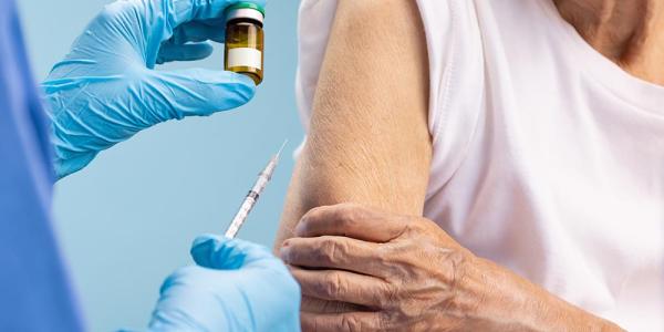 Un asistente sanitario administra una vacuna a una mujer mayor
