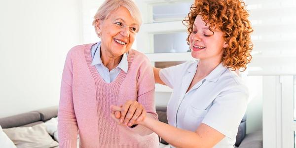 Una cuidadora sostiene la mano de una mujer