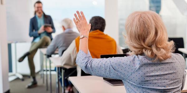 Una mujer levanta la mano en un aula llena de alumnos